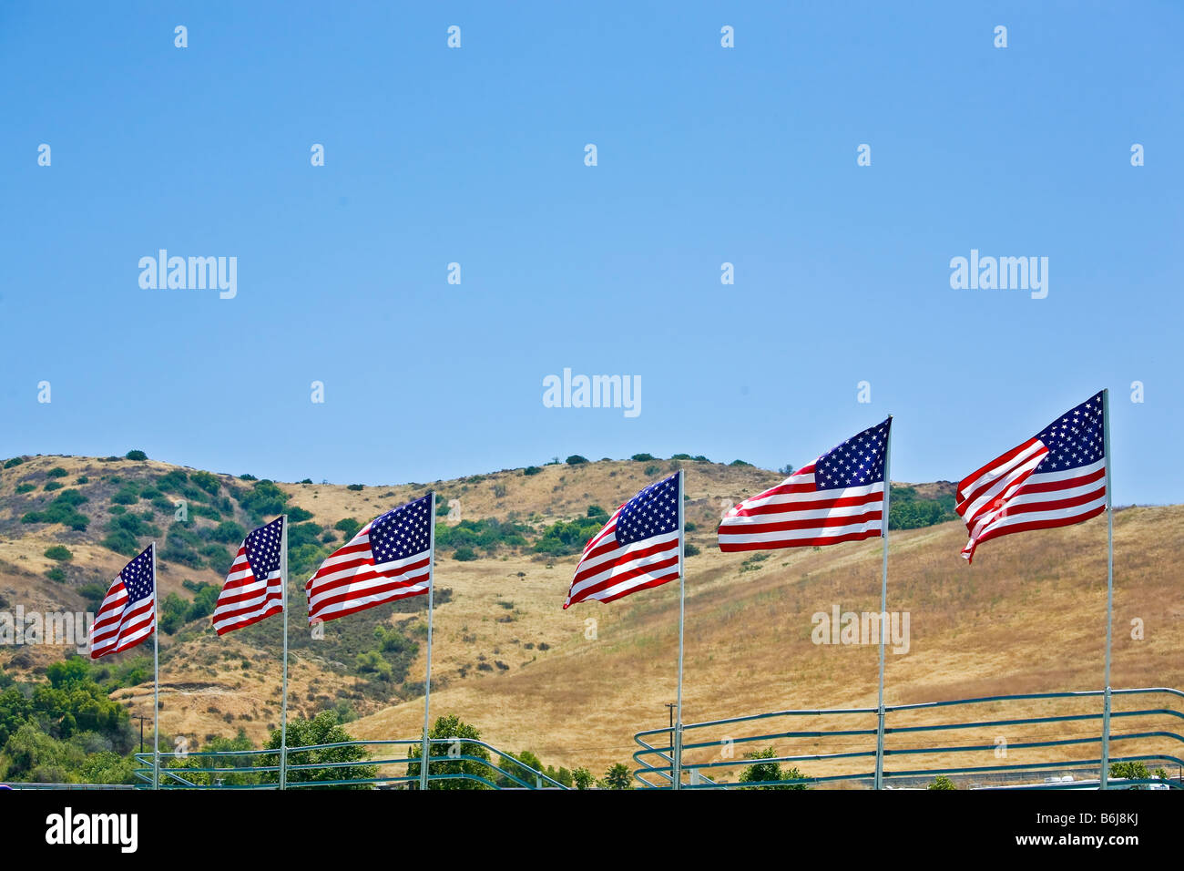 American flags flying against a blue sky and brown hillside Stock Photo ...