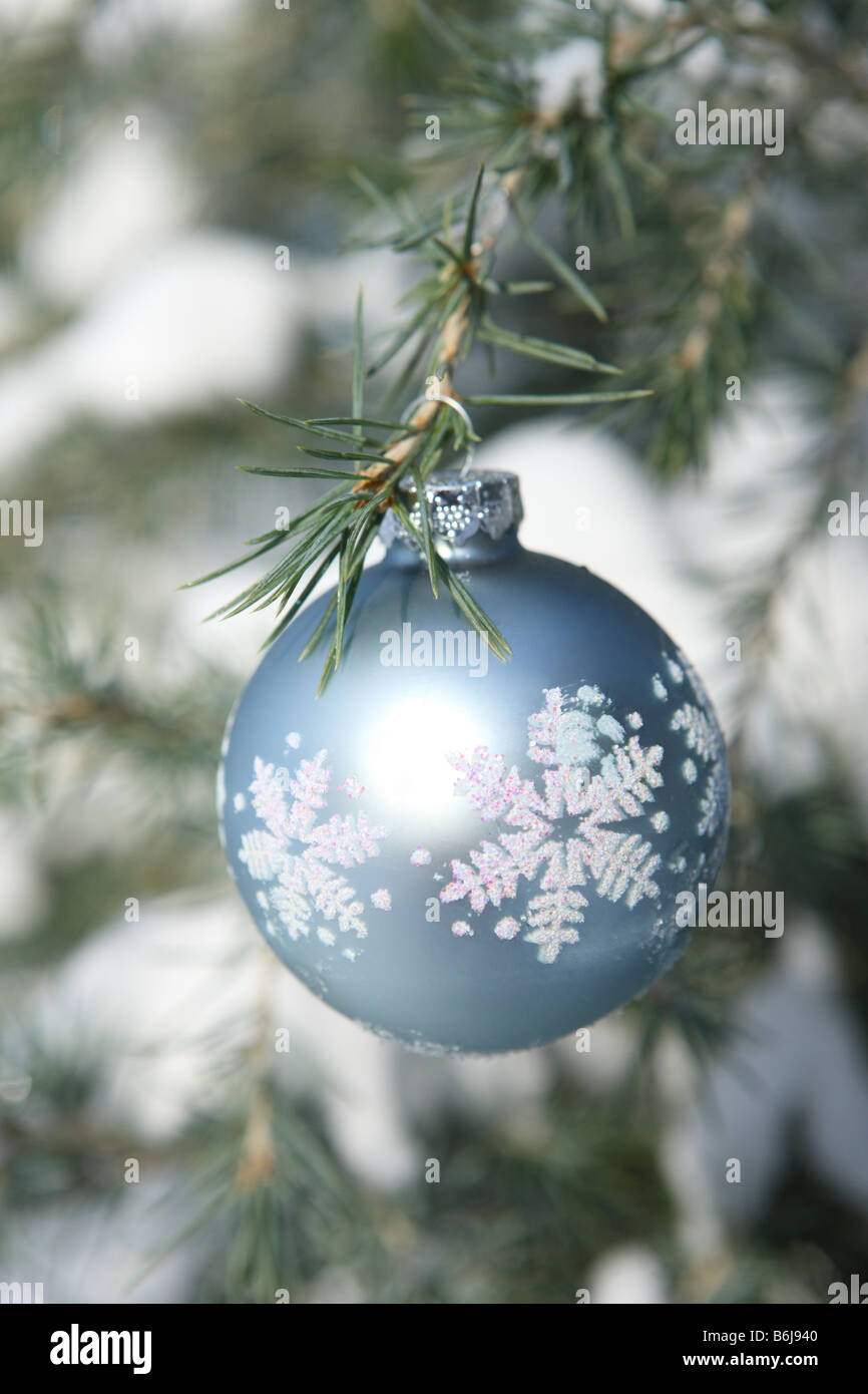 Snowflake Christmas ornament hanging on a snow covered tree Stock Photo