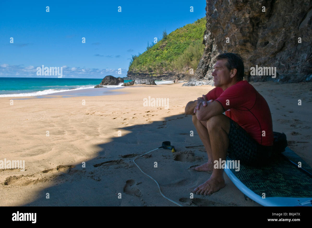 Man sitting on his StandUp Paddle Board, Na Pali coast, Kauai, Hawaii
