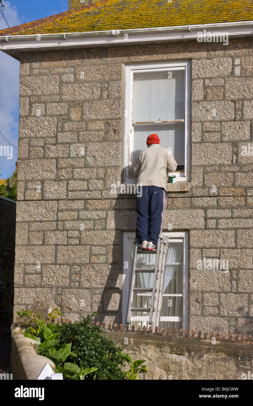 Painter scraping a window frame Stock Photo