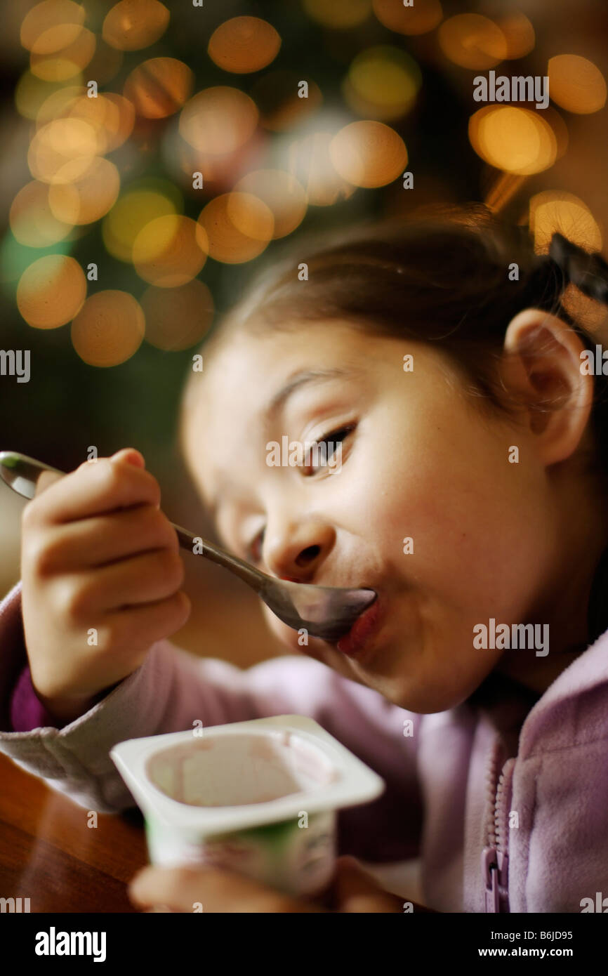 Five year old girl eats yoghurt from pot Stock Photo