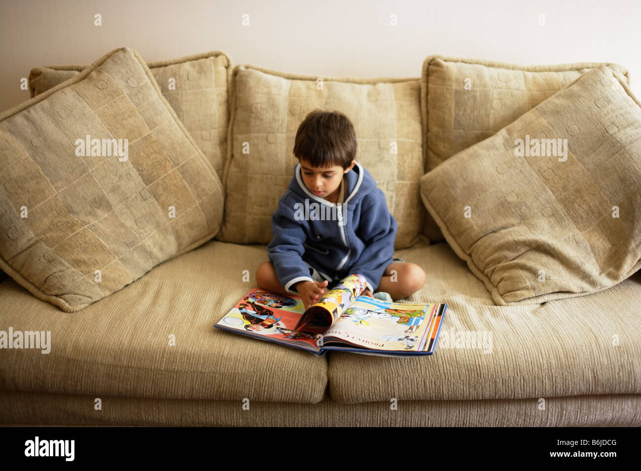 Six year old boy reads on sofa Stock Photo