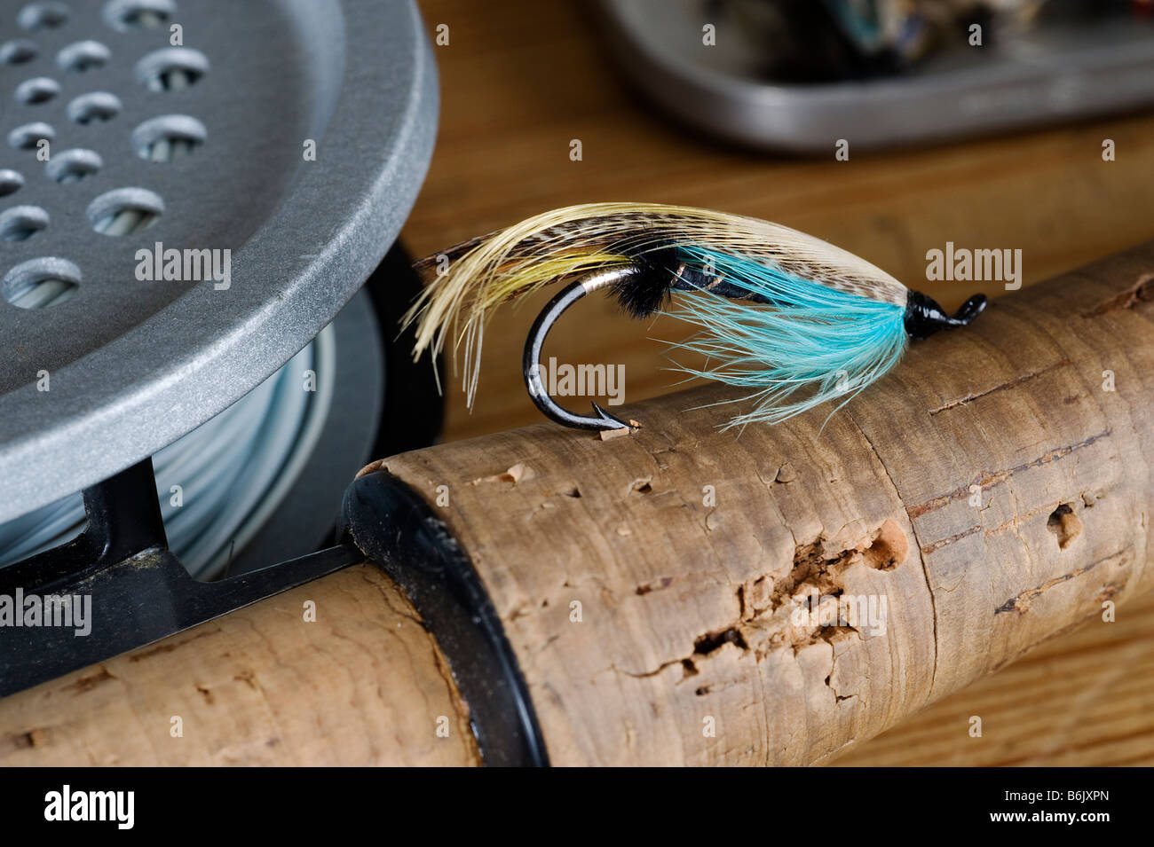 UK.  A salmon fly stuck into the cork handle of a fly fishing rod. Stock Photo