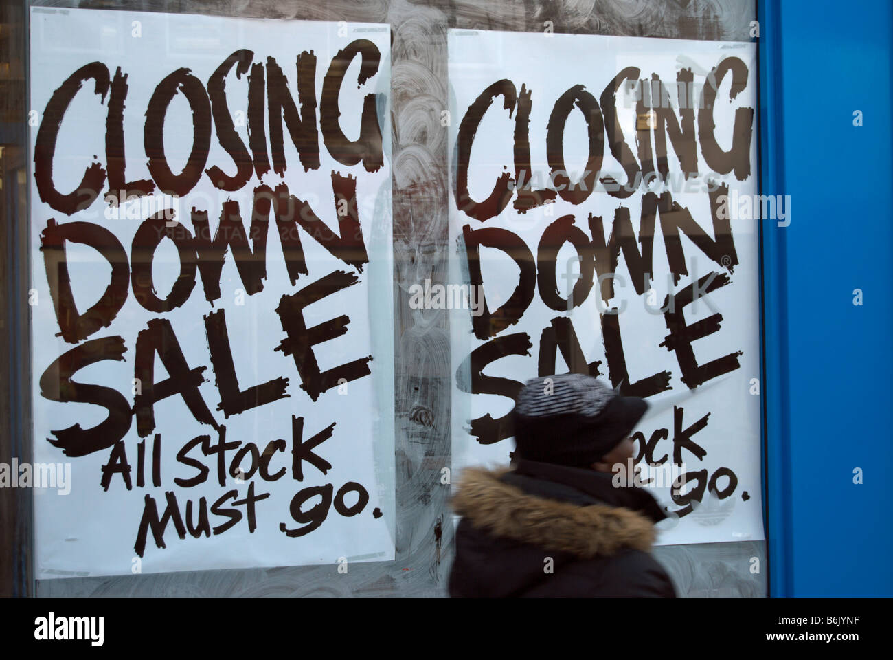 woman passing a closing down sale sign in a shop window in kingston