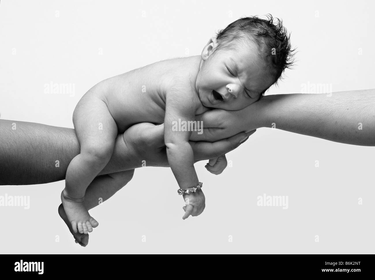 newborn baby in black and white yawning and being held by both parents hands Stock Photo
