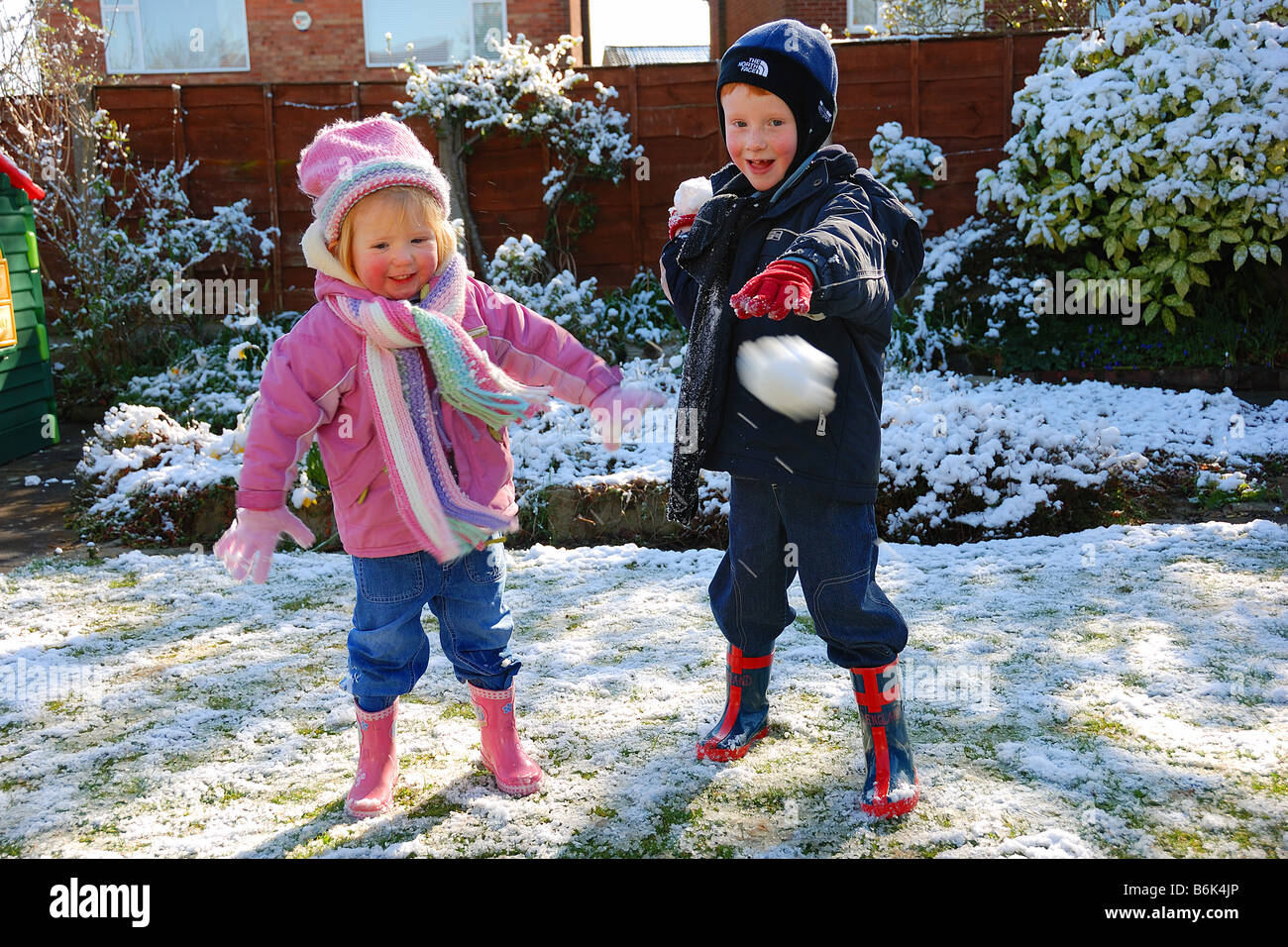two children throwing snowballs in garden Stock Photo Alamy