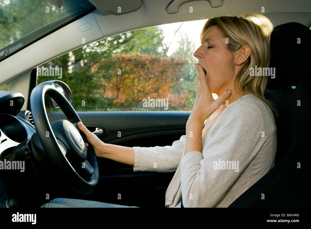 Woman yawning whilst driving Stock Photo