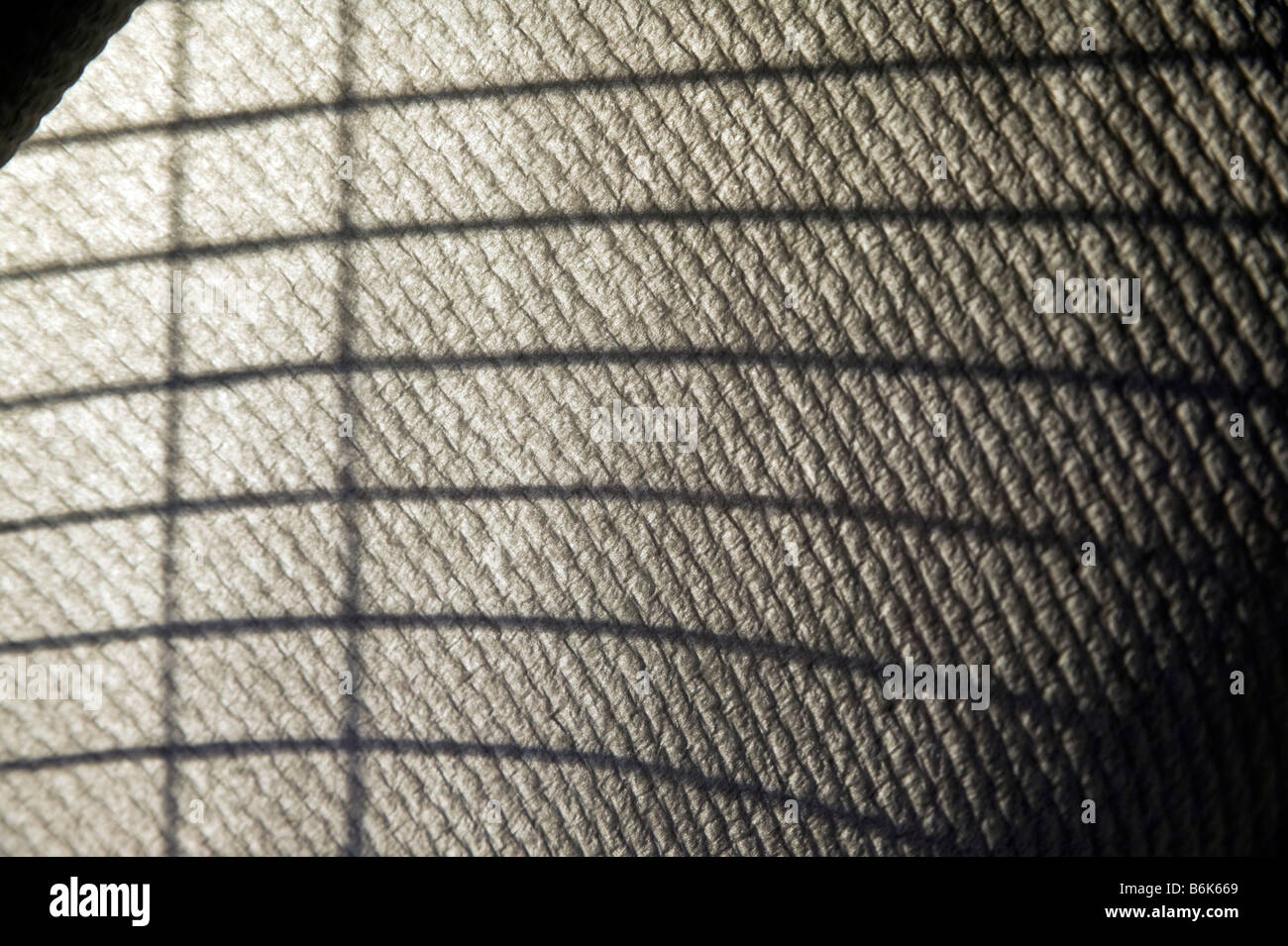 Sunlight streaming through venetian blinds create a striped pattern of shadows on a roll of paper towels. Stock Photo