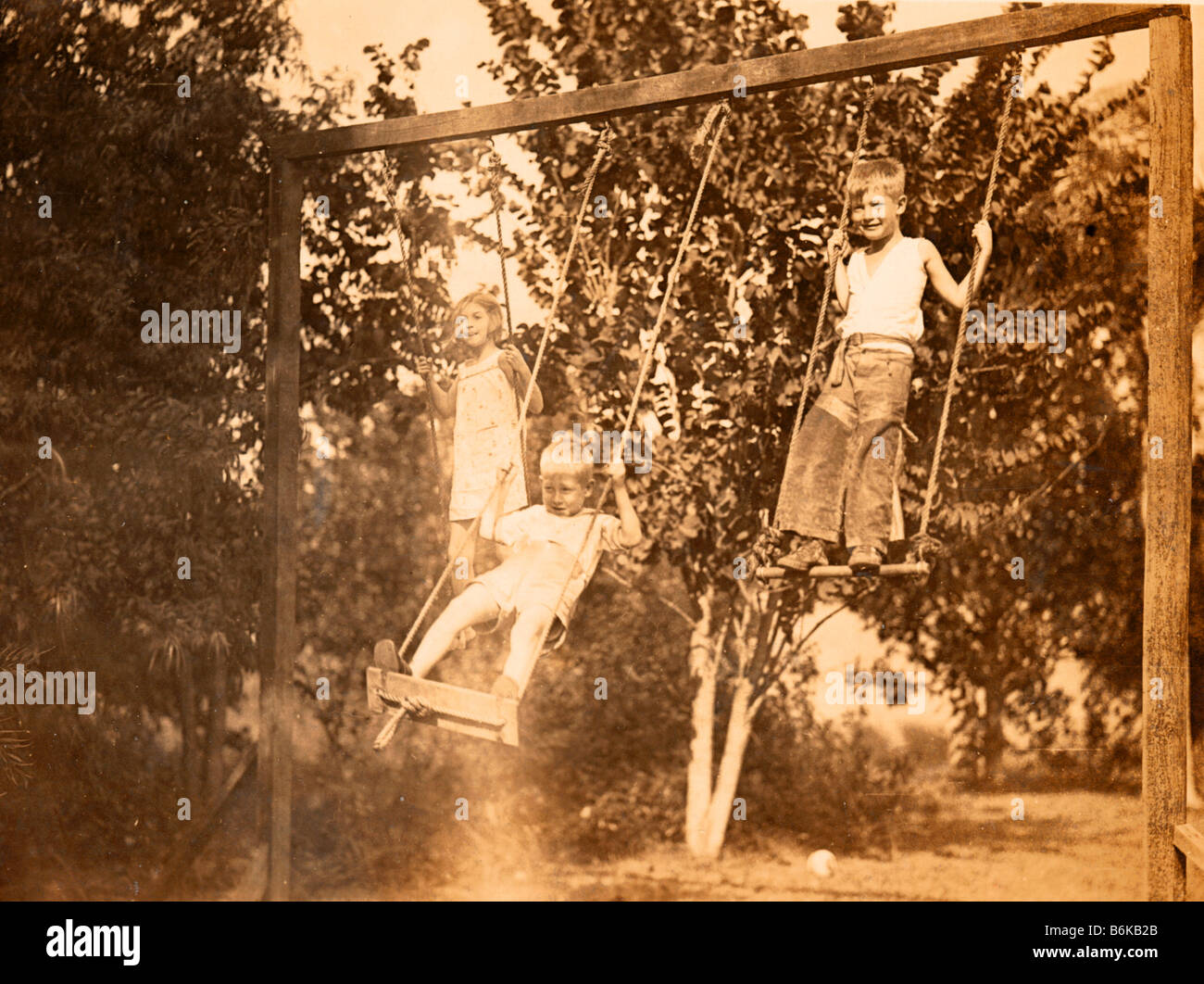 retro photo of three kids on homemade swing circa 1928 Stock Photo