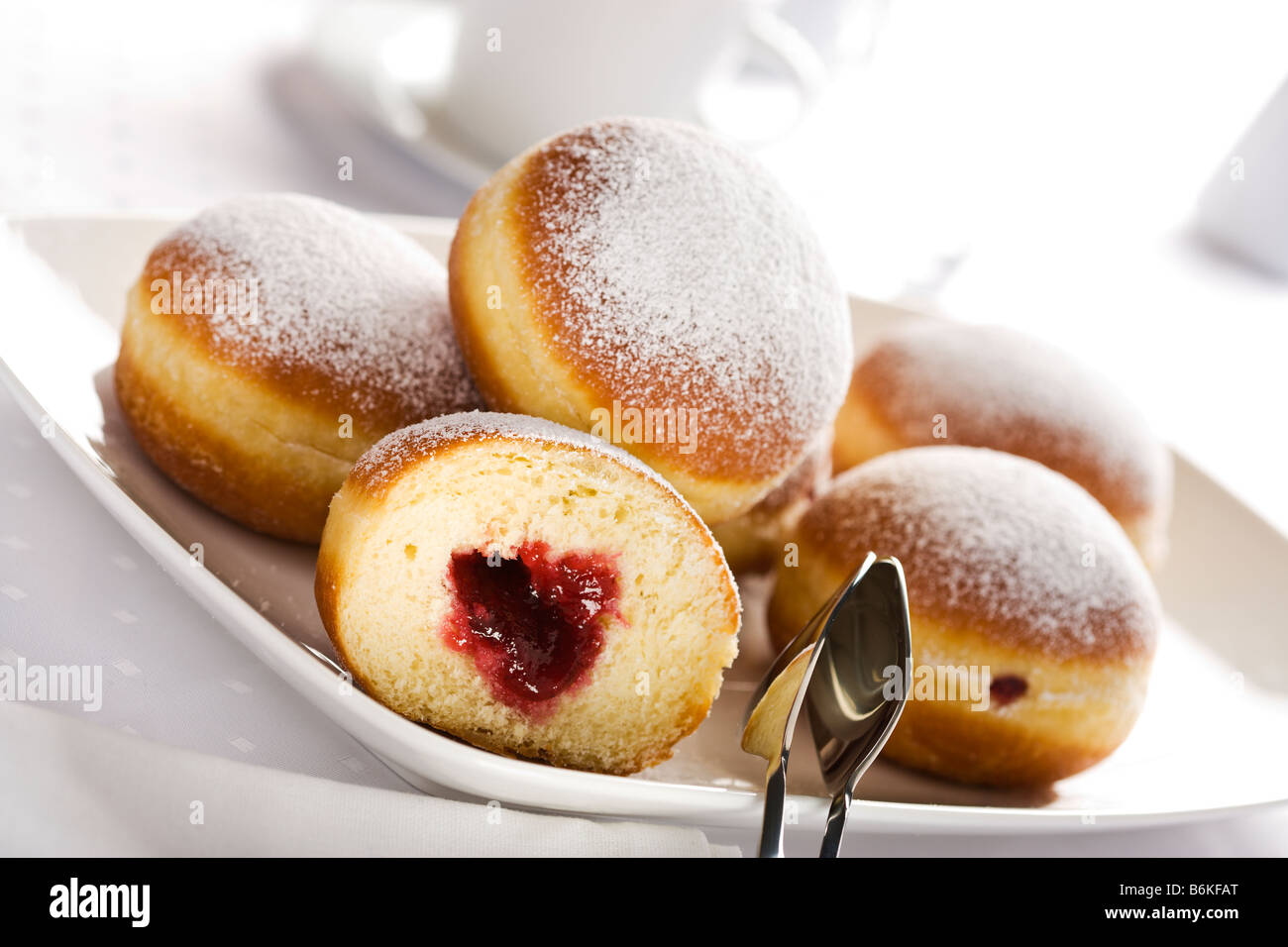 Berliner or Bismarck doughnuts on a plate with cake pliers Stock Photo
