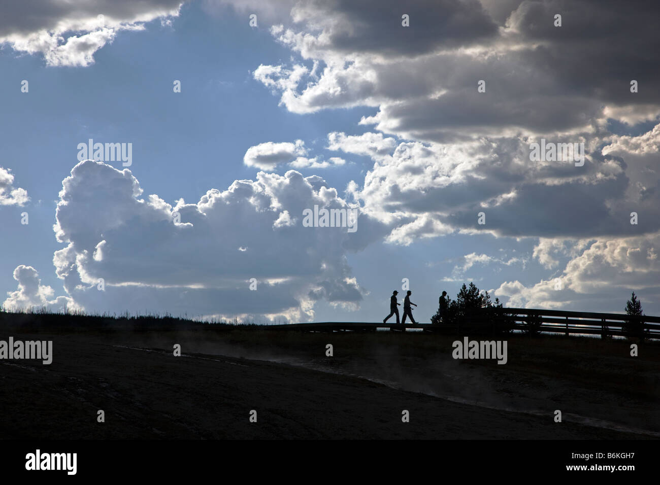 Visitors silhouetted and dramatic sky, Grand Prismatic Spring, Midway Geyser Basin, Yellowstone National Park, Wyoming, USA Stock Photo