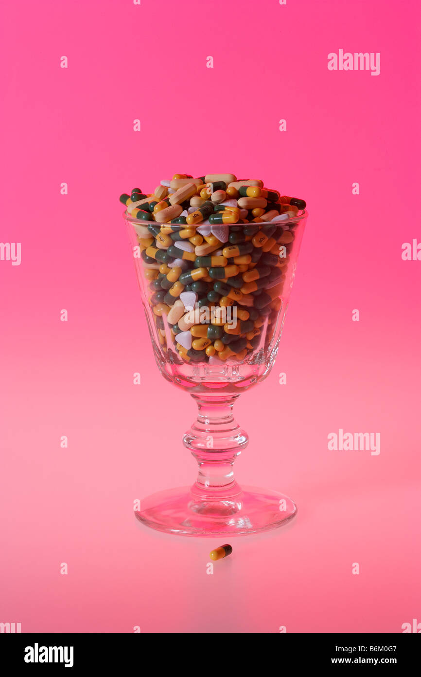 Glass of Painkiller Pills on Pink Background Stock Photo