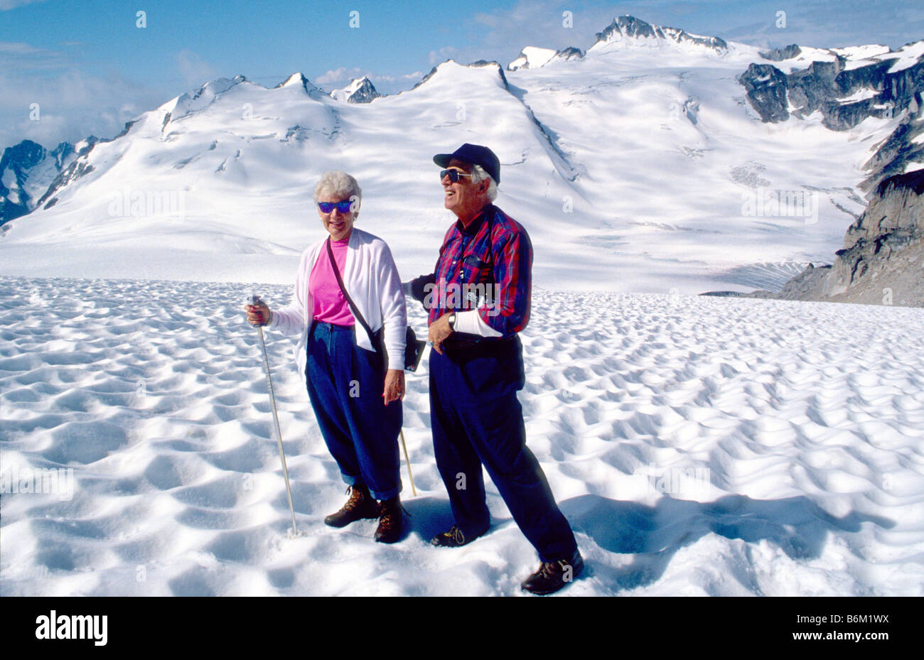 Couple hiking with ski poles on Malloy Glacier in the Bugaboos, Purcell Range, British Columbia, Canada Stock Photo
