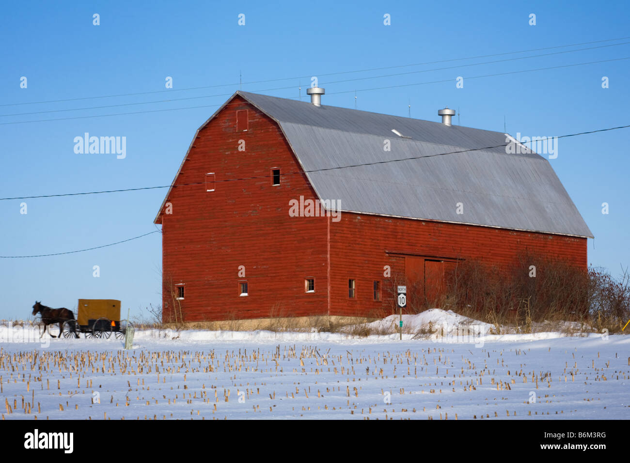 Amish buggy passing big red barn Mohawk Valley New York State Stock