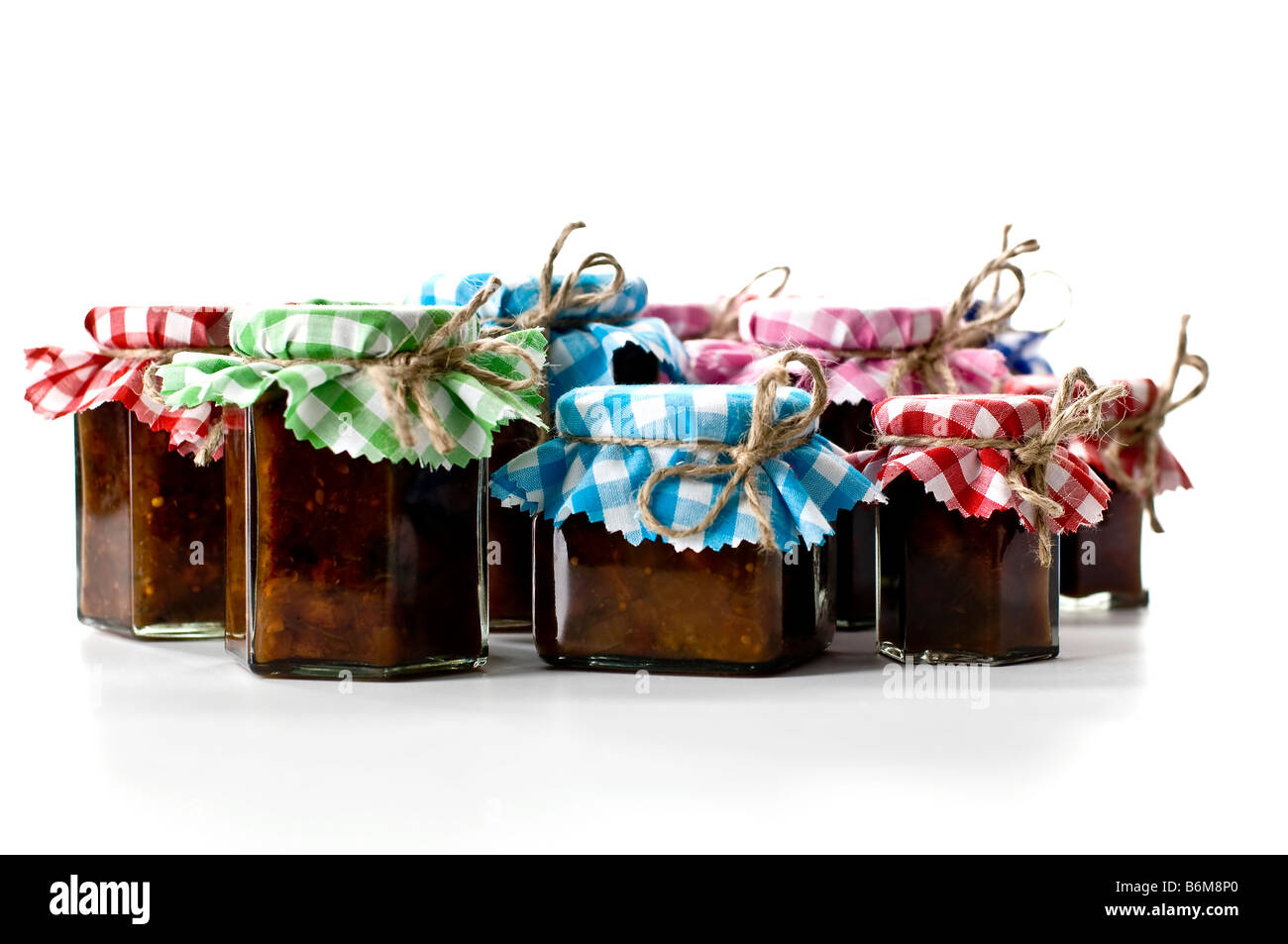 Jars of chutney covered in pretty gingham fabric tied with rustic string. To be given as gifts. Stock Photo
