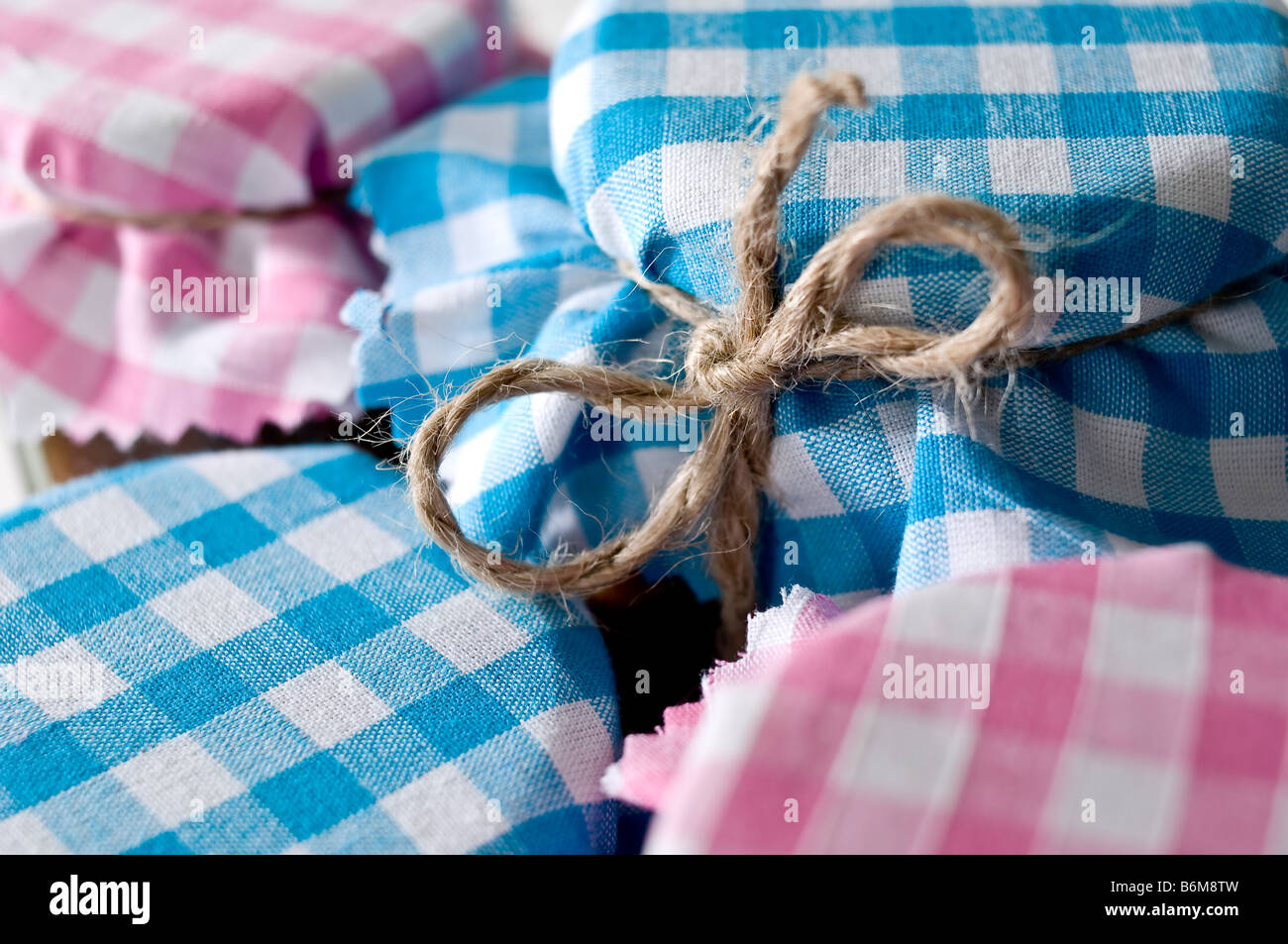Close-up of jars of chutney covered in pretty gingham fabric tied with rustic string. To be given as gifts. Stock Photo