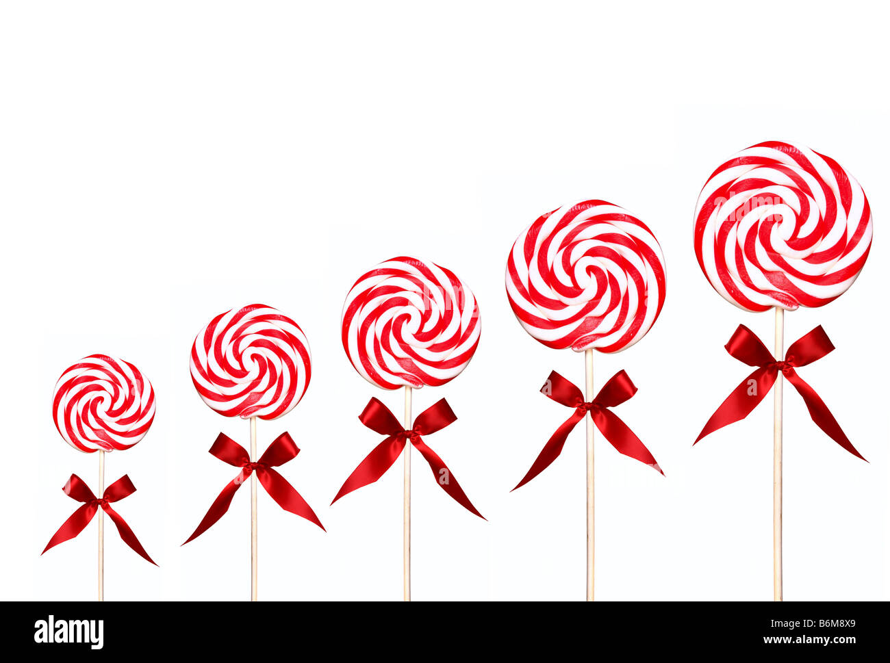Holiday Candy Swirl Lollipops In A Line on White Background With Red Bow  Stock Photo - Alamy