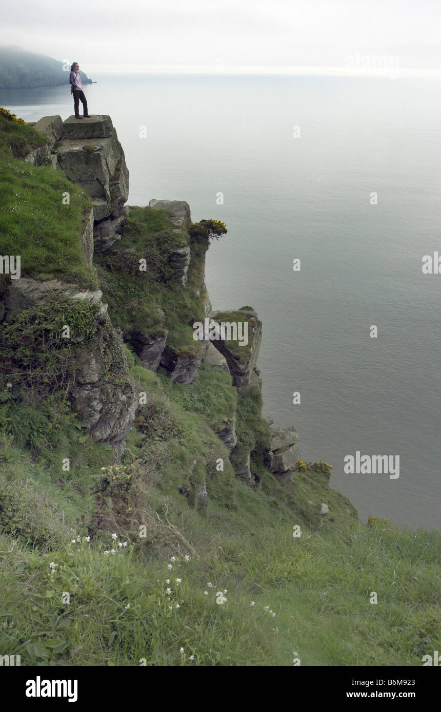 A walker stood on very tall cliffs at Lynmouth in Devon Stock Photo