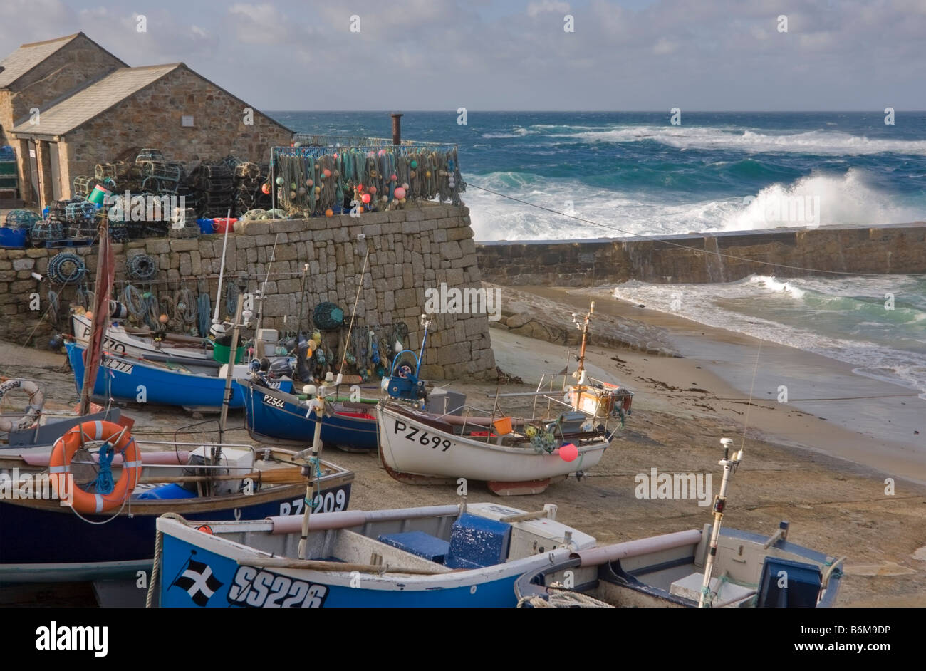 Fishing dinghies drawn up on the beach behind the breakwater at Sennen ...