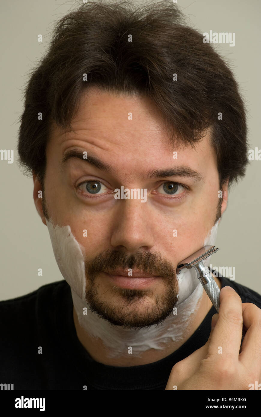 Portrait of Man while wet shaving with a double edge safety razor Stock Photo