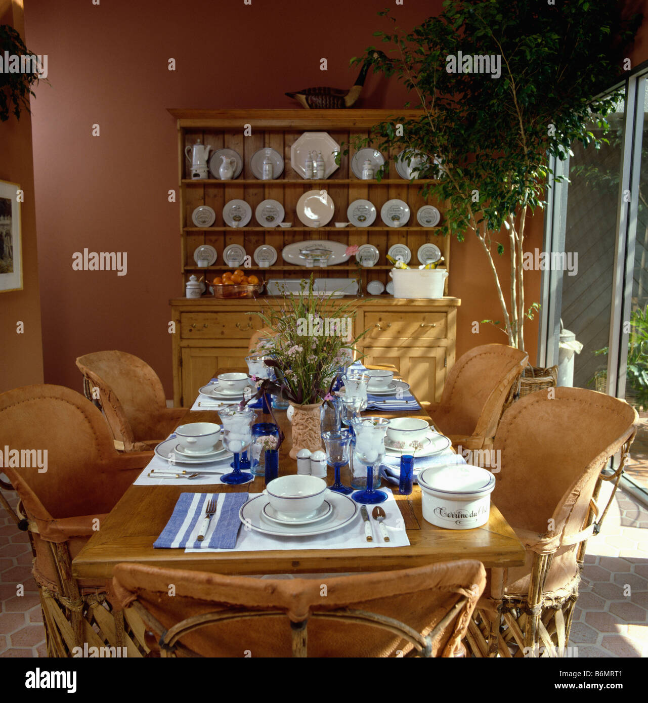 Pale Leather And Cane Mexican Chairs At Table Set For Lunch In Dining Room With Large Dresser At The End Of The Room Stock Photo Alamy