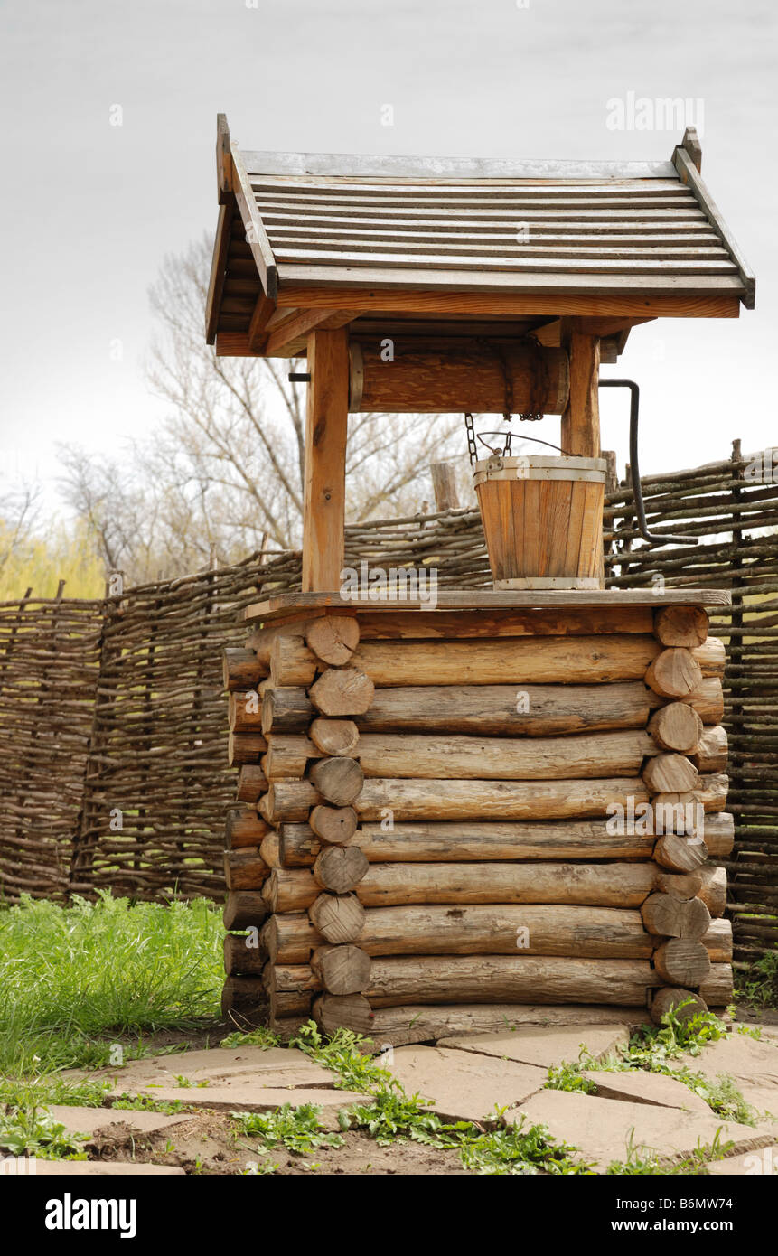 Well An old well made of integral logs with a wooden bucket Stock Photo