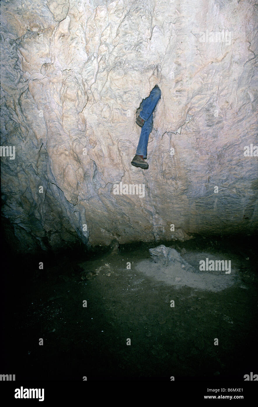 USA NEW MEXICO A spelunker explores a tiny hole in the ceiling of a limestone cave near SAnta Rosa New Mexico Stock Photo