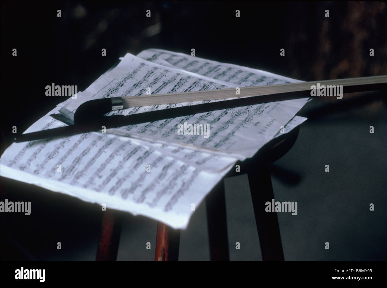 still life with violin bow lying on sheet with music notes on a chair Stock Photo