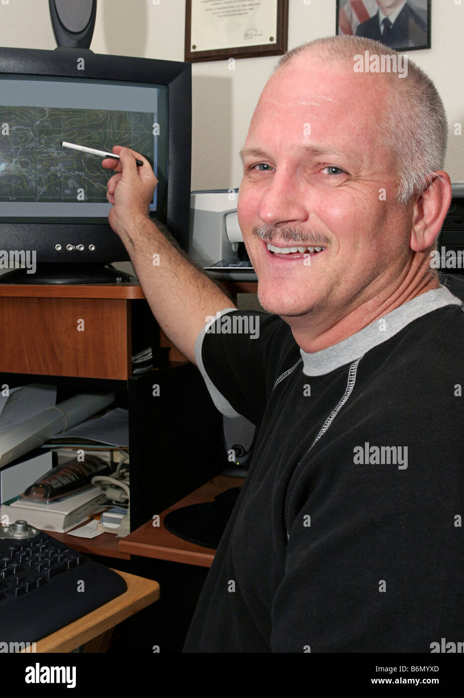 A meteorologist weather man pointing to his computer and smiling He has