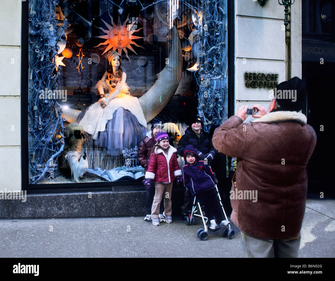 New York evening 5th Avenue family window shopping. Father photographing his family on Fifth Avenue in front of Bergdorf Goodman department store. USA Stock Photo