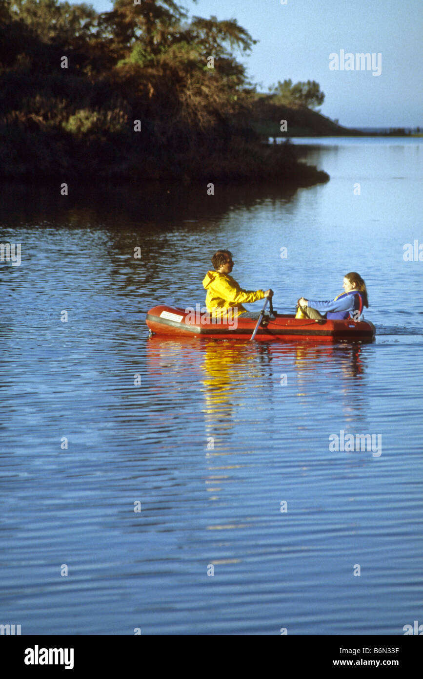 Couple row across lake in inflated rubber boat. Stock Photo