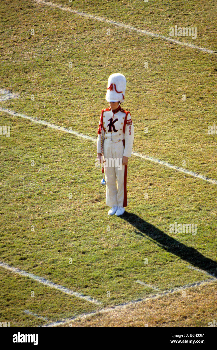 High school band drum major stands at attention on football field grass