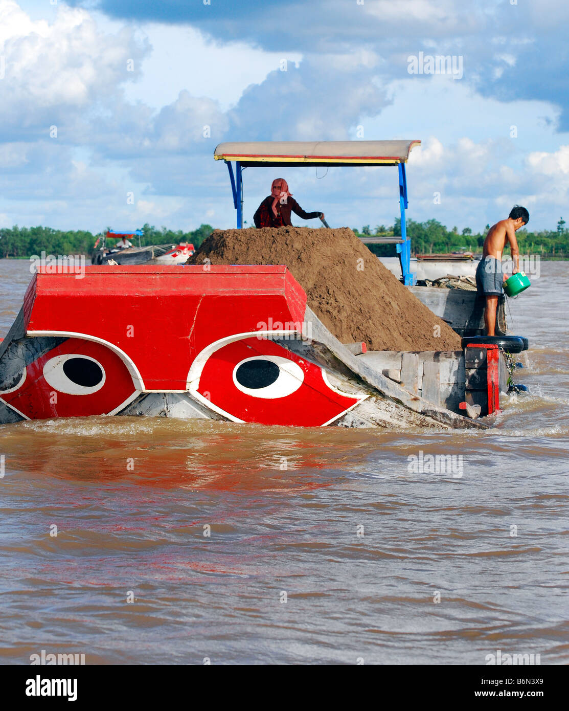 Brightly coloured red river boat carrying topsoil, Tien Giang River