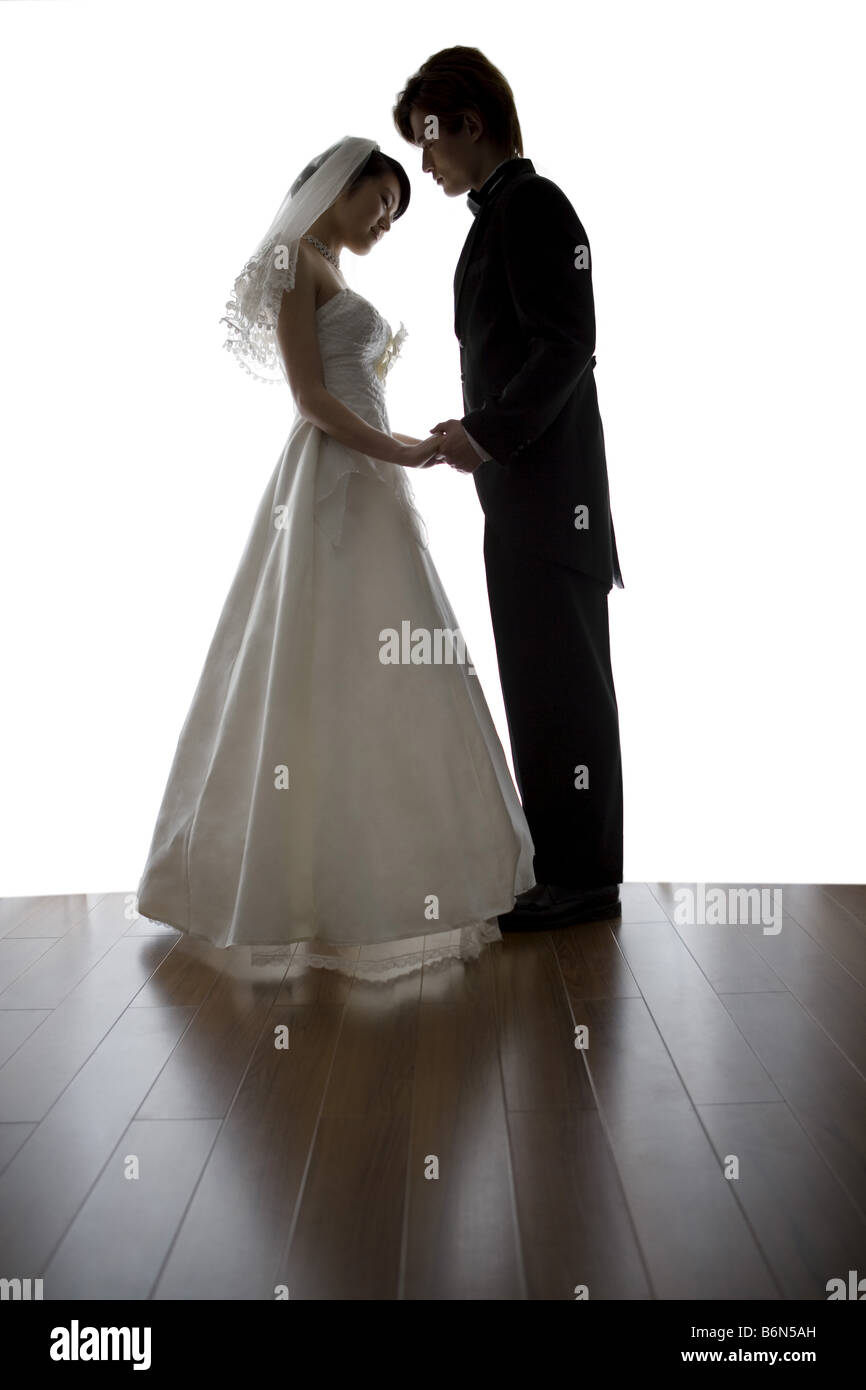 Bride And Groom Standing Face To Face Holding Hands Side View