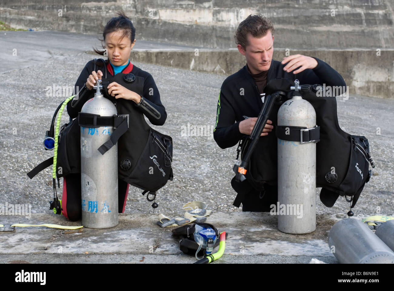 Man and Woman Preparing To Go Scuba Diving, Taiwan, Green Island Stock Photo