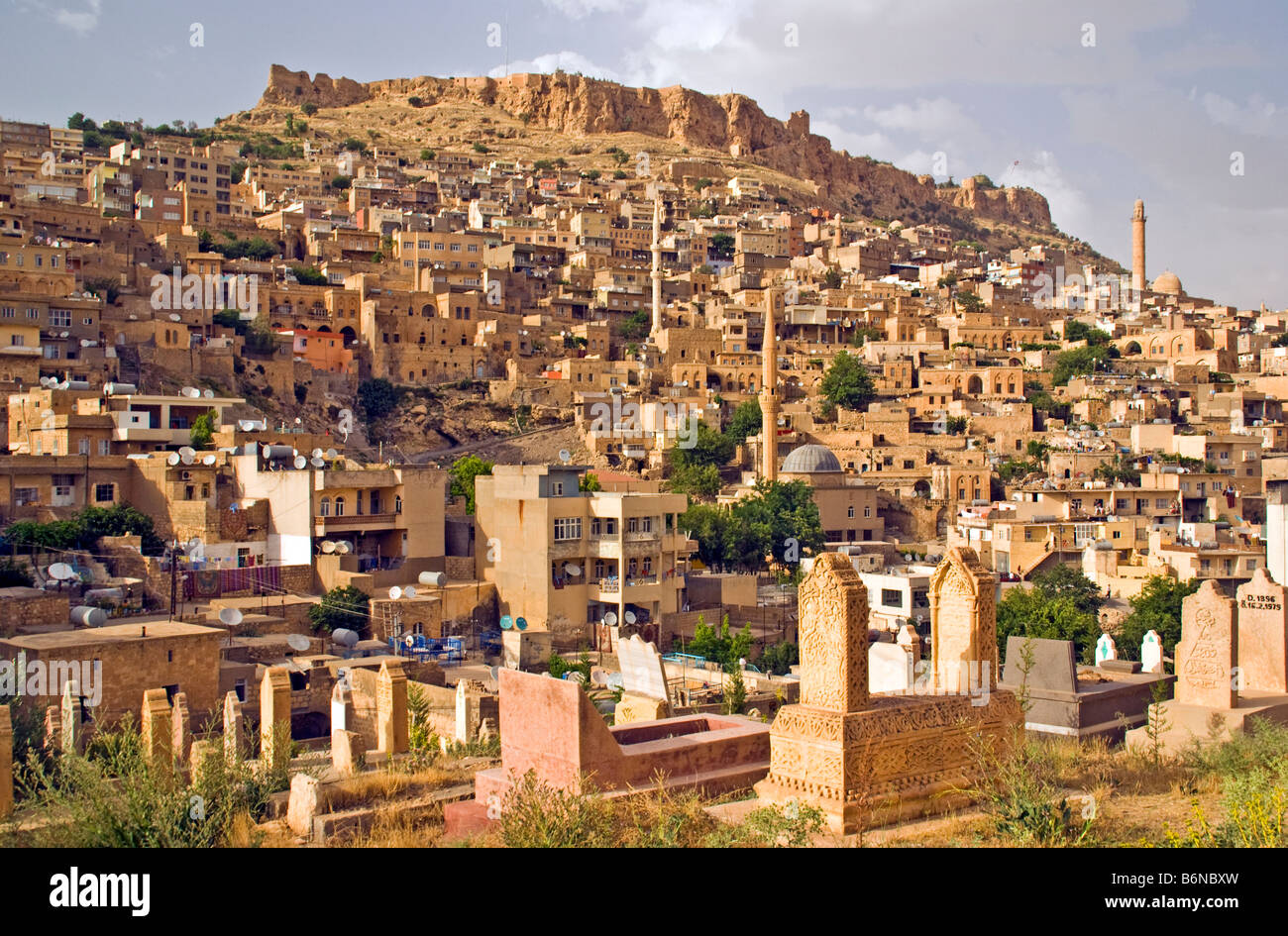 Mardin, houses and minarets of old city below citadel topped mountain, viewed from old cemetery Stock Photo