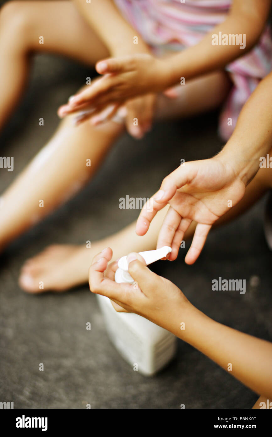 Children apply suncream boy aged six girl aged five Stock Photo