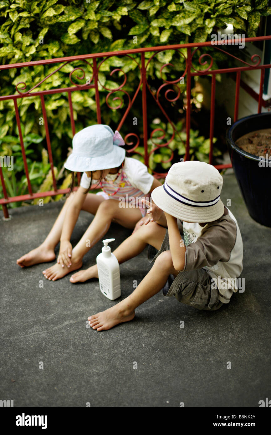 Children apply suncream boy aged six girl aged five Stock Photo