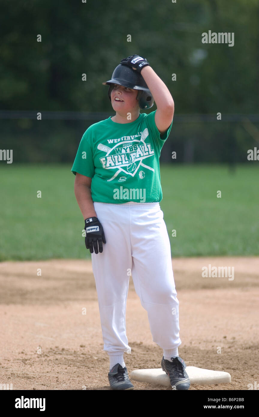 Little League baseball player smiles while standing on second base, sports, games, nine years old, uniform, batting helmet, safe Stock Photo