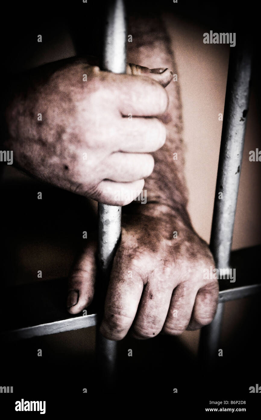 Image of a mans rough hands grasping the steel bars of a prison door from the backside Stock Photo