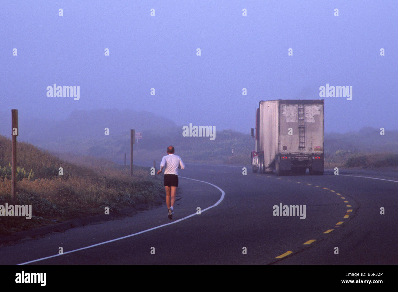 Runner on highway in fog with truck on road near Manila Samoa Peninsula Humboldt County CALIFORNIA Stock Photo