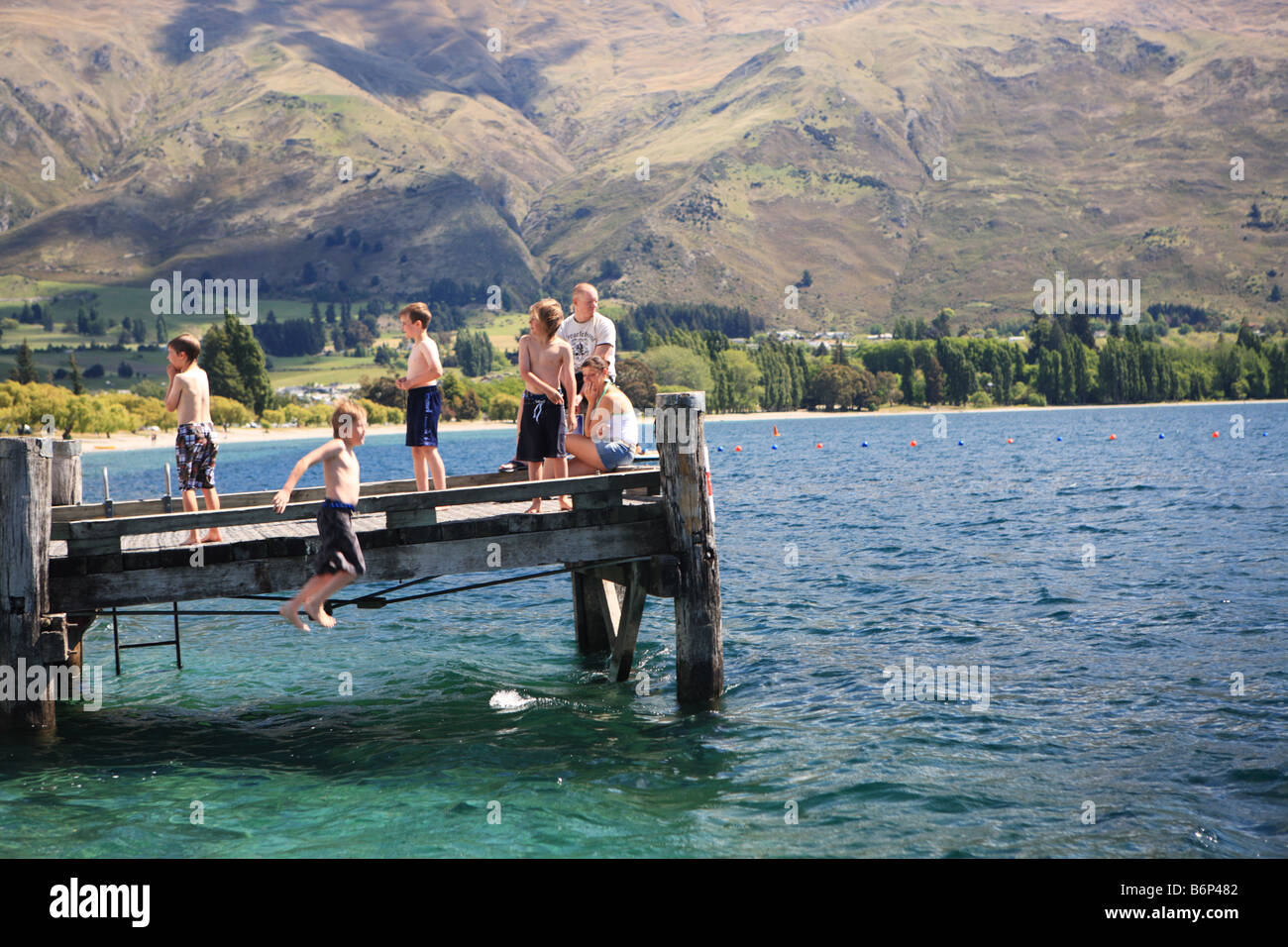 Kids jumping into lake Wanaka, New Zealand Stock Photo