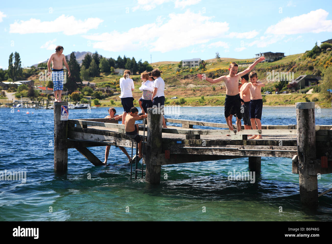 Kids jumping into lake Wanaka, New Zealand Stock Photo