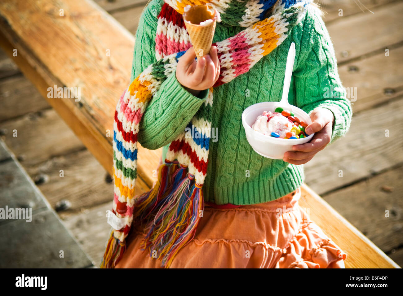 A girl, 4-5 years, enjoys a bowl of ice cream and m&m's on a cold day. Stock Photo