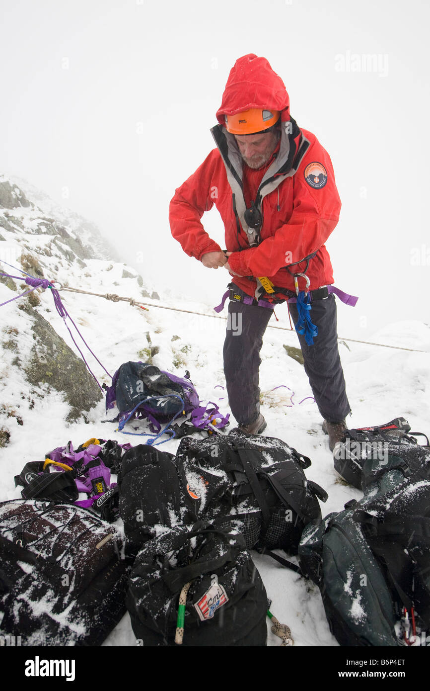 mountain rescue team member prepares to abseil in the snow above Kirkstone near Ambleside in the Lake district UK Stock Photo