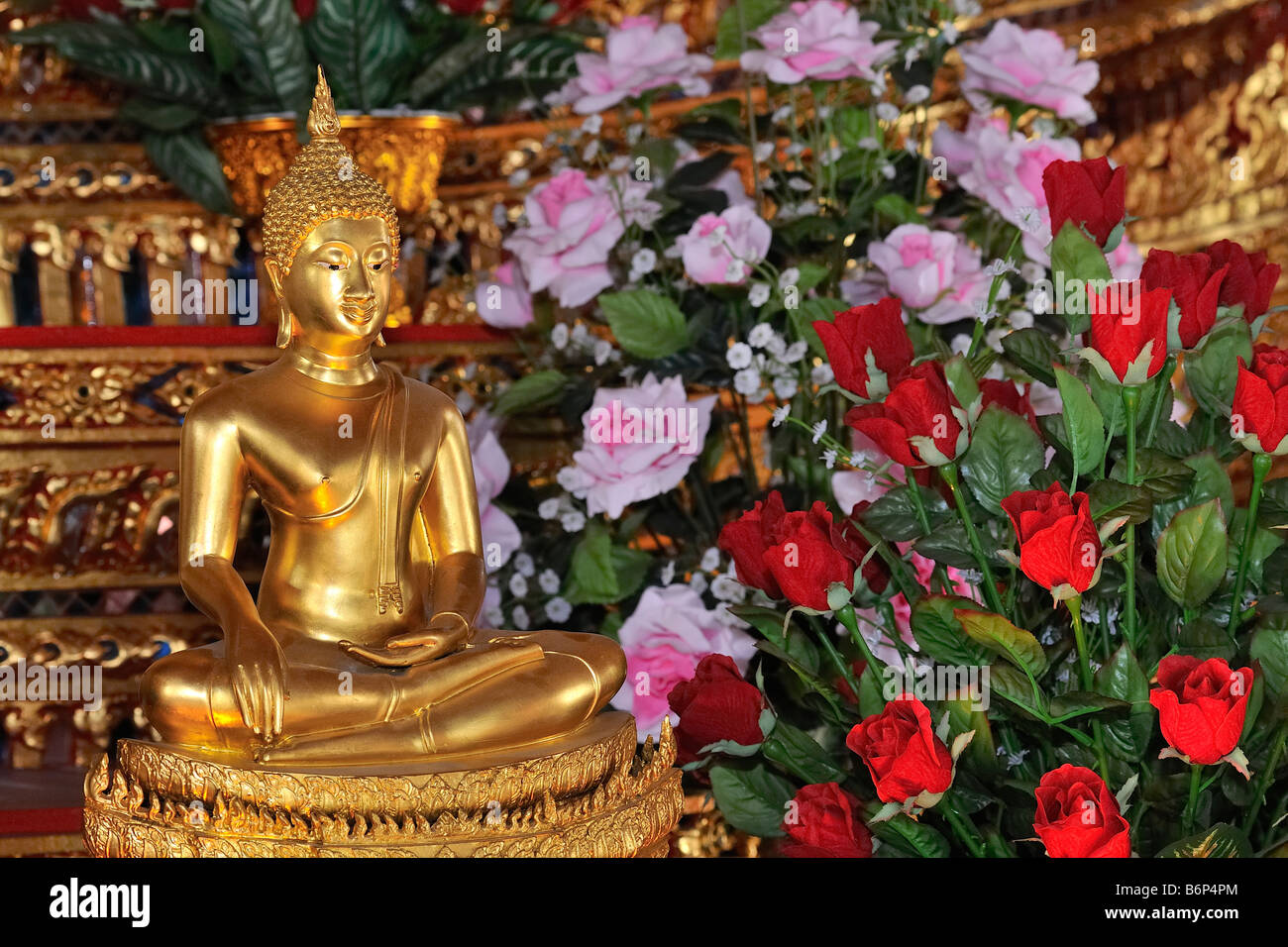 Buddha statue with red and pink roses in buddhist temple in Bangkok's