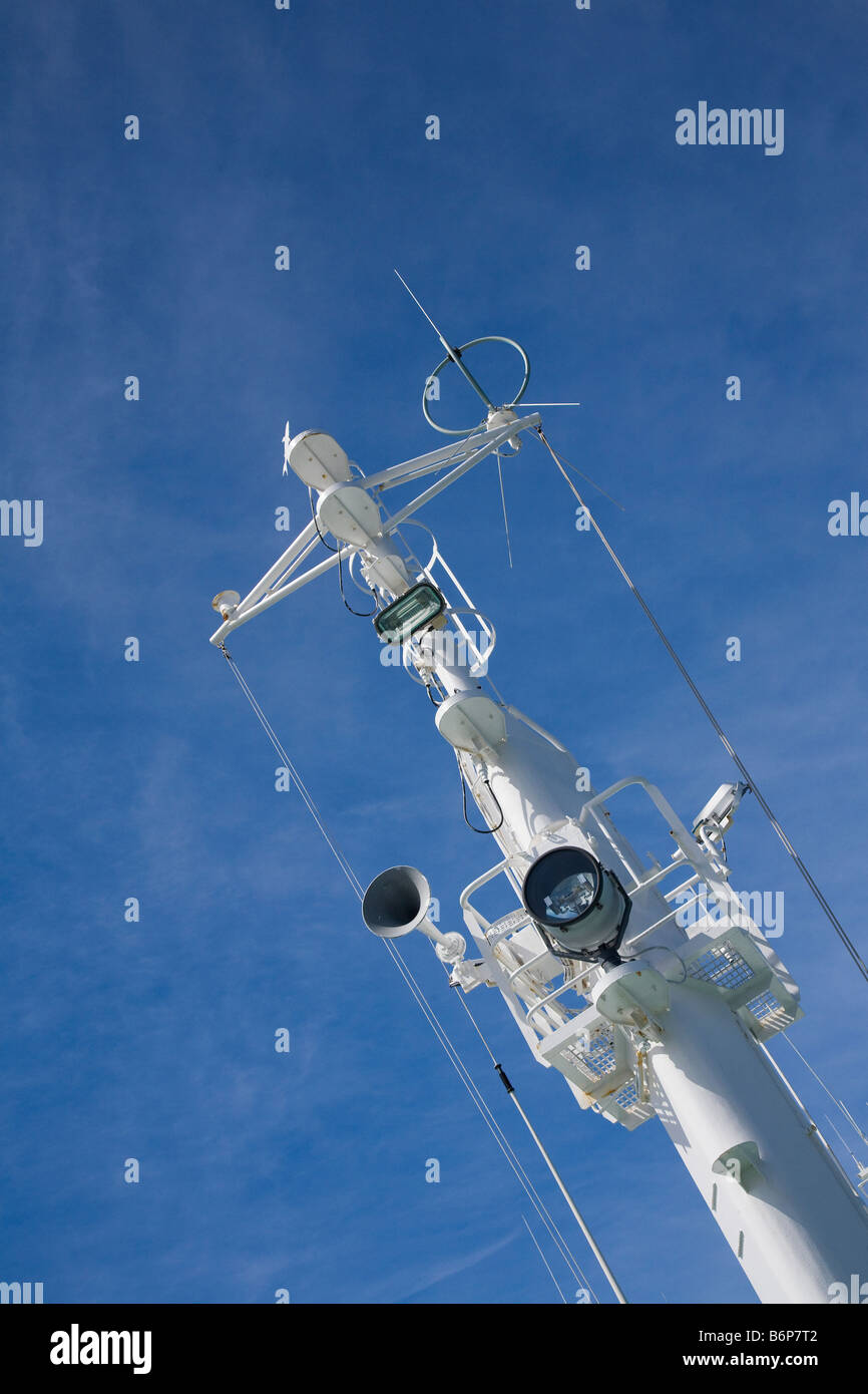 Radio antenna foghorn and ships lights on mast of ocean going vessel Stock Photo