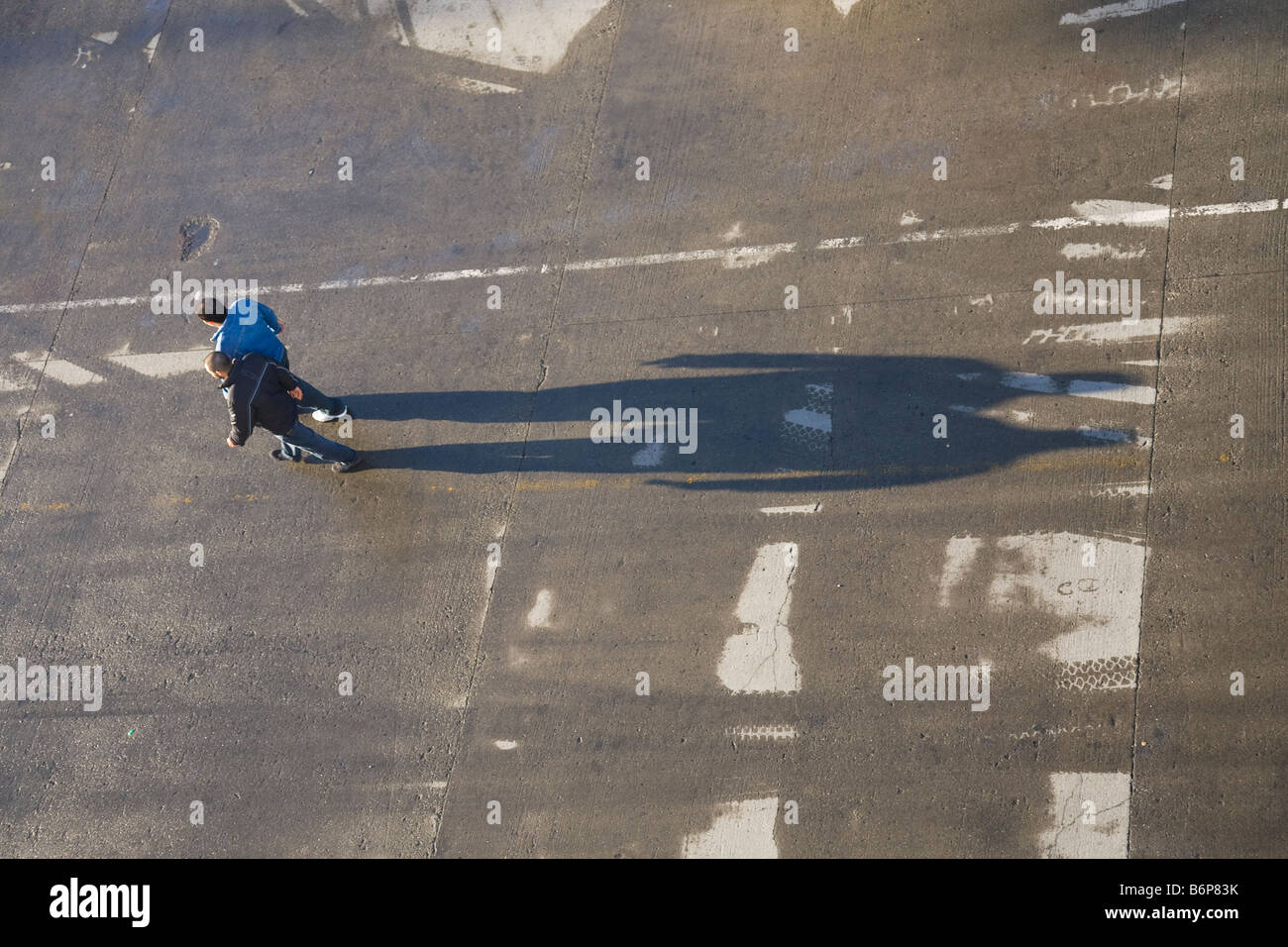 Two men with long shadows walking on docks in early morning light Stock ...