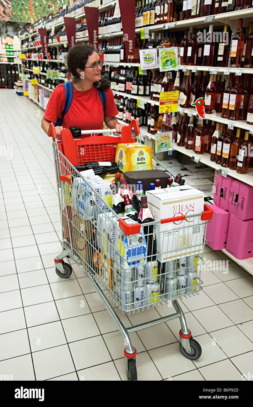 Woman in supermarket shopping for wine and beer to bring back to the UK from France Stock Photo