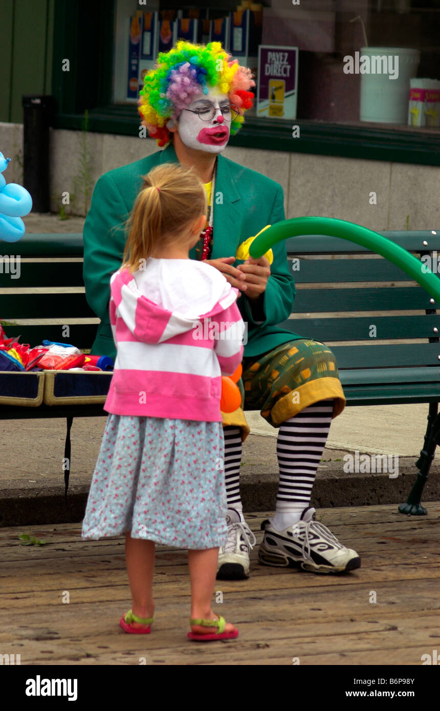 A young girl watching a clown making something with a balloon Stock Photo